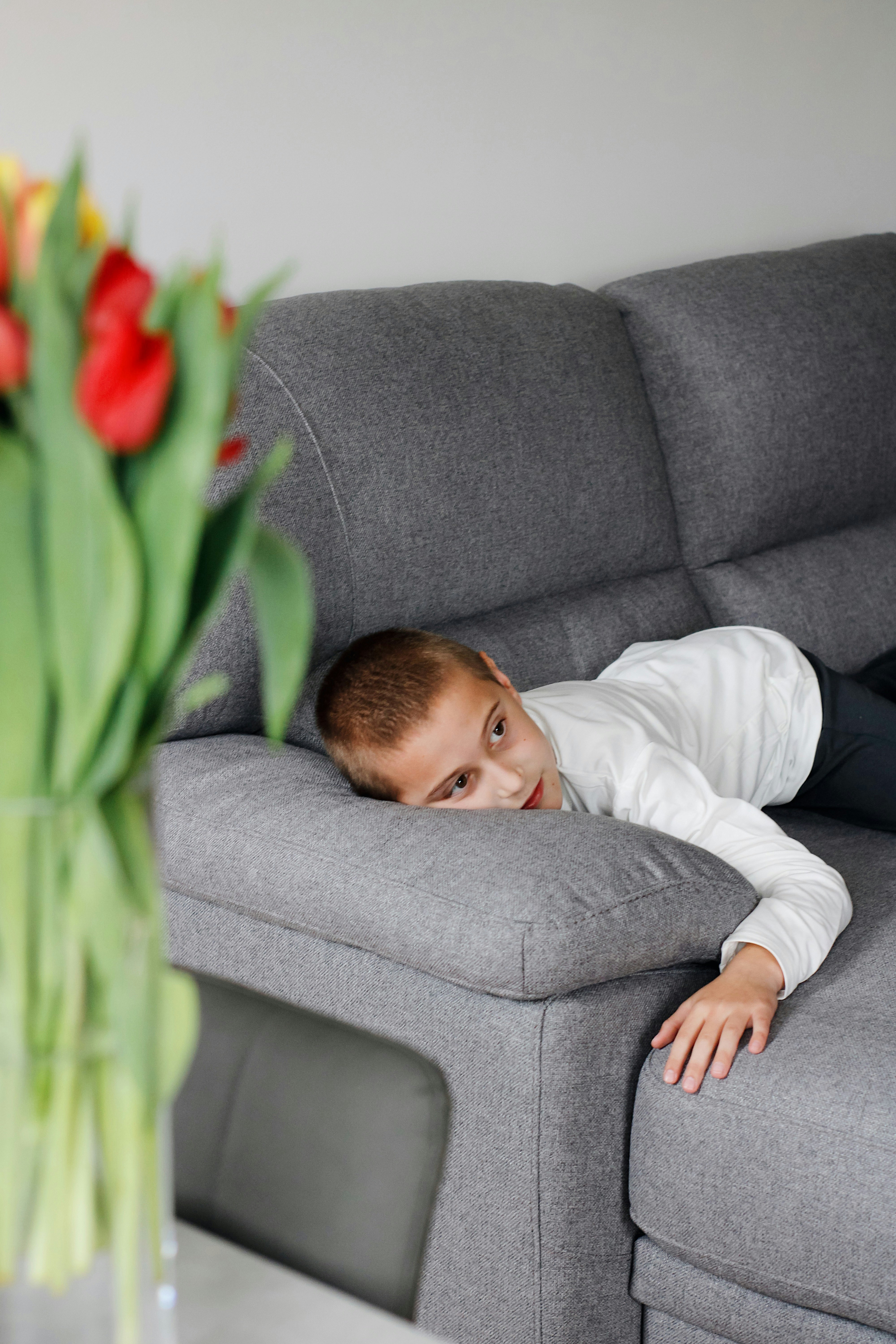 boy in white long sleeve shirt lying on gray sofa